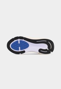 Semelle d'une chaussure de course avec des motifs de traction en caoutchouc noirs, bleus et blancs sur un fond clair uni.