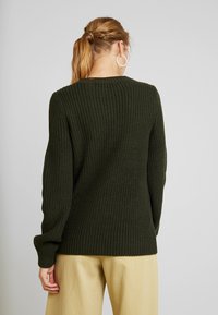 Maglione a maglia verde scuro con una texture a coste e maniche lunghe. Presenta un collo rotondo e una vestibilità comoda.