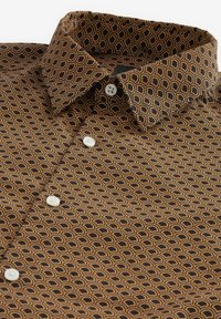 Camisa marrón de botones con un patrón de semicírculos dorados superpuestos, con cuello esparcido y botones blancos. Textura de tela suave.