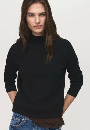Black, lightweight sweater with a high neckline, long sleeves, and a relaxed fit, paired with denim jeans. Smooth texture and minimal design.