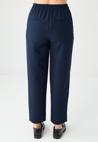 Granatowe spodnie z elastycznym pasem, dwoma tylnymi kieszeniami i prostym krojem nogawek, wykonane z gładkiego, lekkiego materiału.