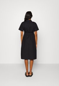 Vestido preto de manga curta em corte solto com cintura cinturada, comprimento até o joelho e gola. Tecido liso sem padrões visíveis.