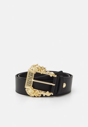 Zwarte leren riem met een sierlijke gouden gesp gegraveerd met het Versace Jeans Couture-logo, opgerold en geplaatst tegen een effen achtergrond.
