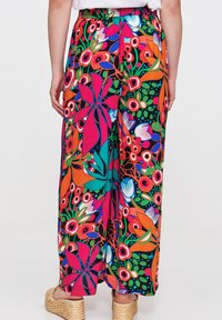 Luftige, weite Hosen mit einem lebhaften Blumenmuster in mehreren Farben auf schwarzem Hintergrund. Elastischer Bund für angenehmen Tragekomfort.