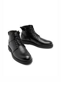 Czarne skórzane botki za kostkę o teksturowanym wykończeniu, z sznurowaniem i bocznym zamkiem błyskawicznym. Gumowa podeszwa z białymi detalami szycia.