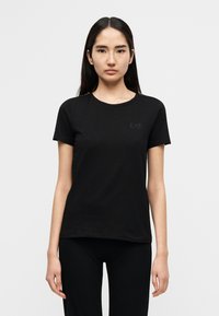 Μαύρο βαμβακερό t-shirt με στρογγυλή λαιμόκοψη, κοντά μανίκια και διακριτικό λογότυπο EA7 στο στήθος. Απλός, εφαρμοστός σχεδιασμός χωρίς σχέδια ή διακοσμητικά στοιχεία.