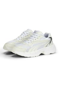 Baskets blanches en maille et synthétique avec un embout arrondi, des accents texturés et un détail argenté sur le côté. Elles comportent des lacets blancs et une semelle épaisse.