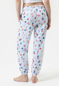 Pantalons de pyjama bleu clair avec un motif rayé et des imprimés de macarons multicolores. Dotés d'une taille élastique et de poignets élastiques aux chevilles.