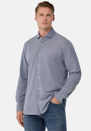 Hellblaue button-up Hemd aus strukturiertem Stoff, mit einem Kragen und langen Ärmeln, kombiniert mit Jeans.