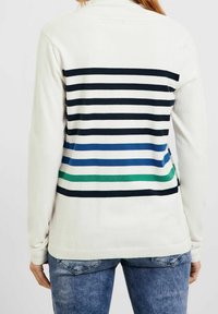 Maglione a maniche lunghe color crema con un design a righe sul retro che presenta tonalità di blu navy, blu e verde. Realizzato in materiale morbido con orlo a costine.