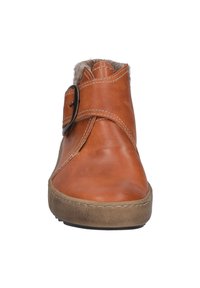 Braune Leder-Stiefeletten mit runder Zehenpartie, dekorativer Schnalle und Futter aus Fell am oberen Rand. Genähte Details entlang der Sohle. Flache Laufsohle.