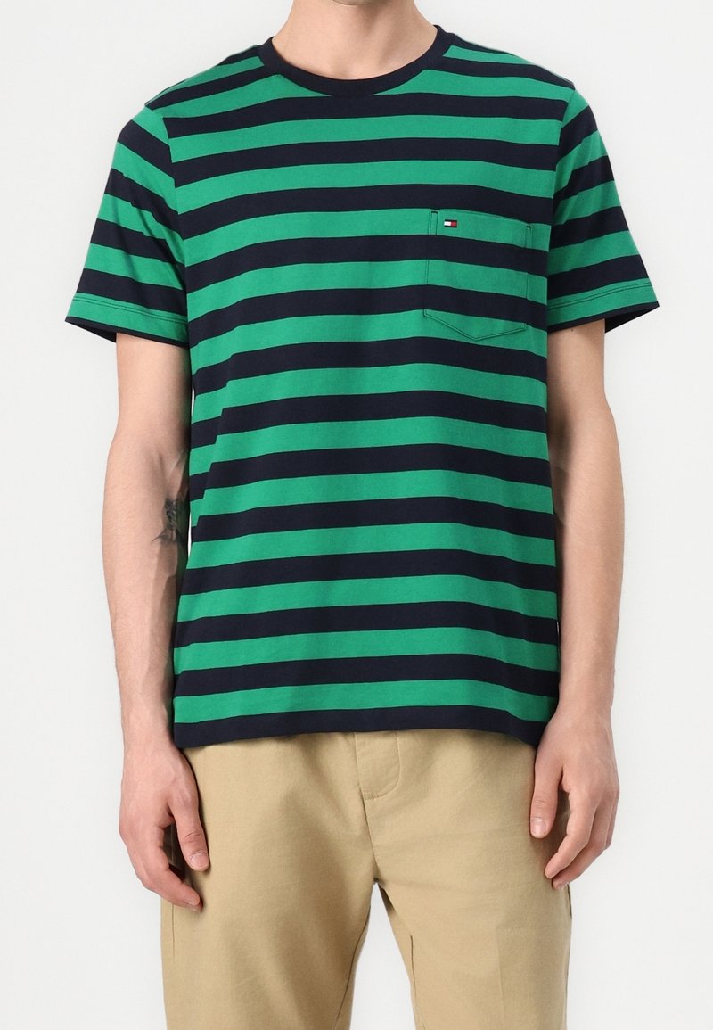 Vihreä ja laivastonsininen raidallinen lyhythihainen t-paita, jossa on pyöreä kaula-aukko ja pieni rintatasku. Valmistettu pehmeästä puuvillakankaasta, rento malli.