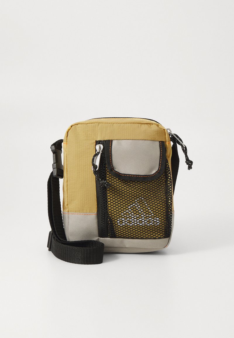Kompakte Crossbody-Tasche aus gelbem und grauem Stoff. Verfügt über einen verstellbaren Schulterriemen, eine Netztasche auf der Vorderseite und einen Reißverschluss. Texturiertes Material mit Akzentnähten.