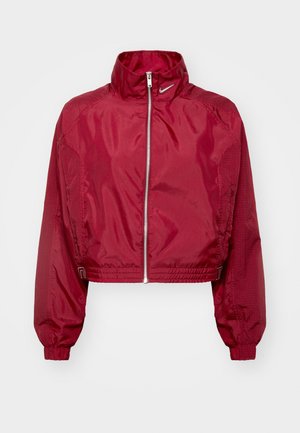 Kuttet rød Nike-jakke med høy krage, glidelås lukking, elastiske ermer og teksturerte sidepaneler. Glatt, skinnende stofffinish.