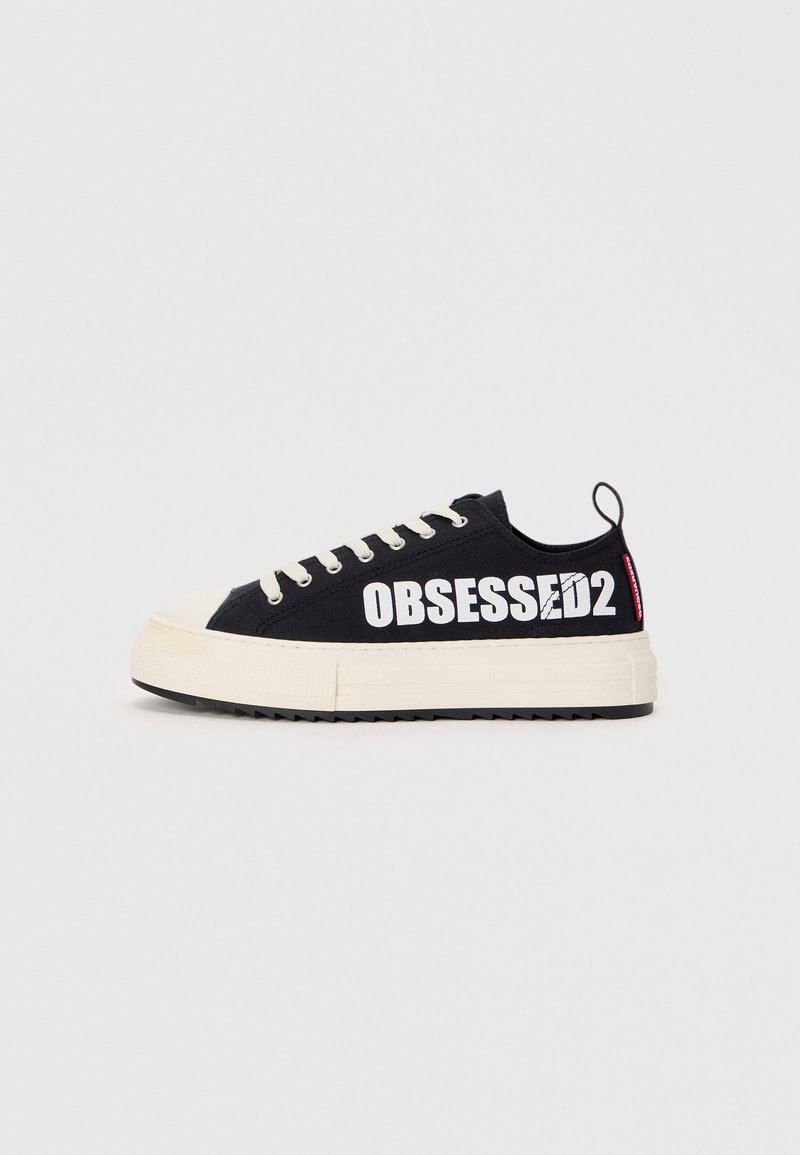 Baskets en toile noires avec le texte blanc "OBSESSED2", semelle en caoutchouc crème, lacets plats et boucle de tirage arrière. Vue de côté affichée.