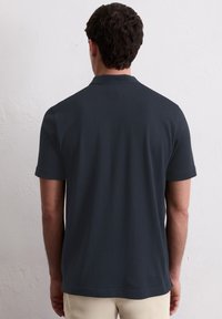 Dunkelgraues Kurzarm-Polohemd mit weicher Textur, schickem Design und einem kleinen Etikett am Hals. Mit geradem Schnitt am Saum.