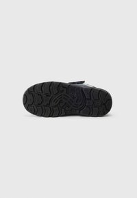 Semelle en caoutchouc noir avec un motif de bande de roulement profond et des accents texturés. Tige bleu clair et blanche avec fermeture à bande velcro.