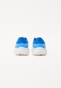 Baskets de sport bleues avec un supérieur texturé, une semelle intermédiaire blanche et des accents jaunes sur la semelle en caoutchouc. Conçues pour le confort et la stabilité.