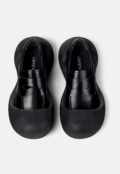 Scarpe nere con tomaia in pelle liscia e suola in gomma tessurizzata, con punta arrotondata e una fascia decorativa sul collo del piede.