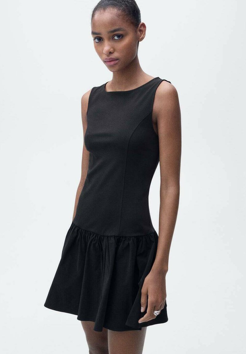 Black dress with a fitted bodice and a flared, ruffled skirt. Made of smooth fabric, featuring a crew neck and no sleeves.