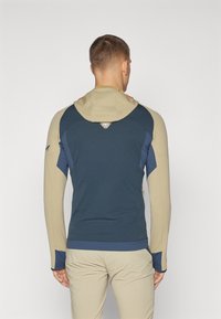 Hooded jacket with a navy blue body and beige sleeves, featuring a textured fabric and subtle branding on the back.