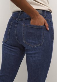 Tunna blå denimjeans med en mjuk textur, som har bakfickor och kontrasterande sömmar. Midjan är hög med en vanlig passform.