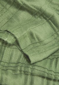 Tissu vert texturé avec un motif en chevrons, présentant des fils doux et tissés ainsi que des variations subtiles de teinte et de brillance.