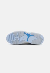 Bílá gumová podrážka s modrým logem Jumpman, texturovaný design s různými vzory, včetně kruhových a cikcakových prvků.
