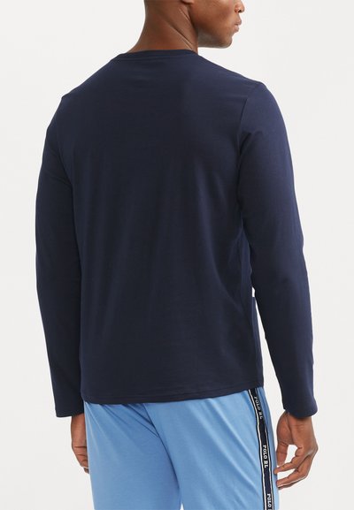 Navy blue long-sleeve shirt made of soft fabric, featuring a round neckline and a relaxed fit, paired with light blue shorts with side stripes.
