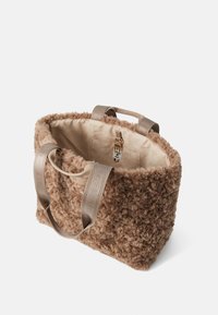 Bruine fluffy tote bag met een pluche buitenkant, twee stoffen handvatten en een beige interieur met een zak en een sluiting voor veiligheid.