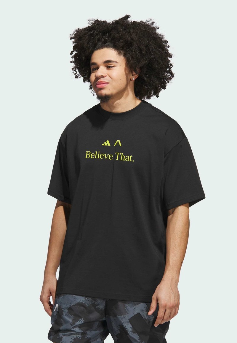 T-shirt nera a maniche corte con la scritta "Believe That." in testo giallo neon; design rilassato e scollatura a girocollo.