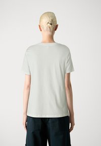 T-shirt en coton vert clair avec un col rond classique, des manches courtes et une coupe droite. Texture lisse, sans motifs ni accents visibles.