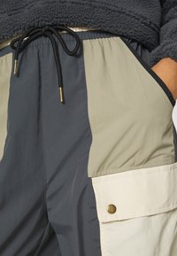 Färgblockerade shorts med avsnitt i marinblått, olivgrönt och krämfärgat; har elastisk midja, snörning och knappfickdetalj.