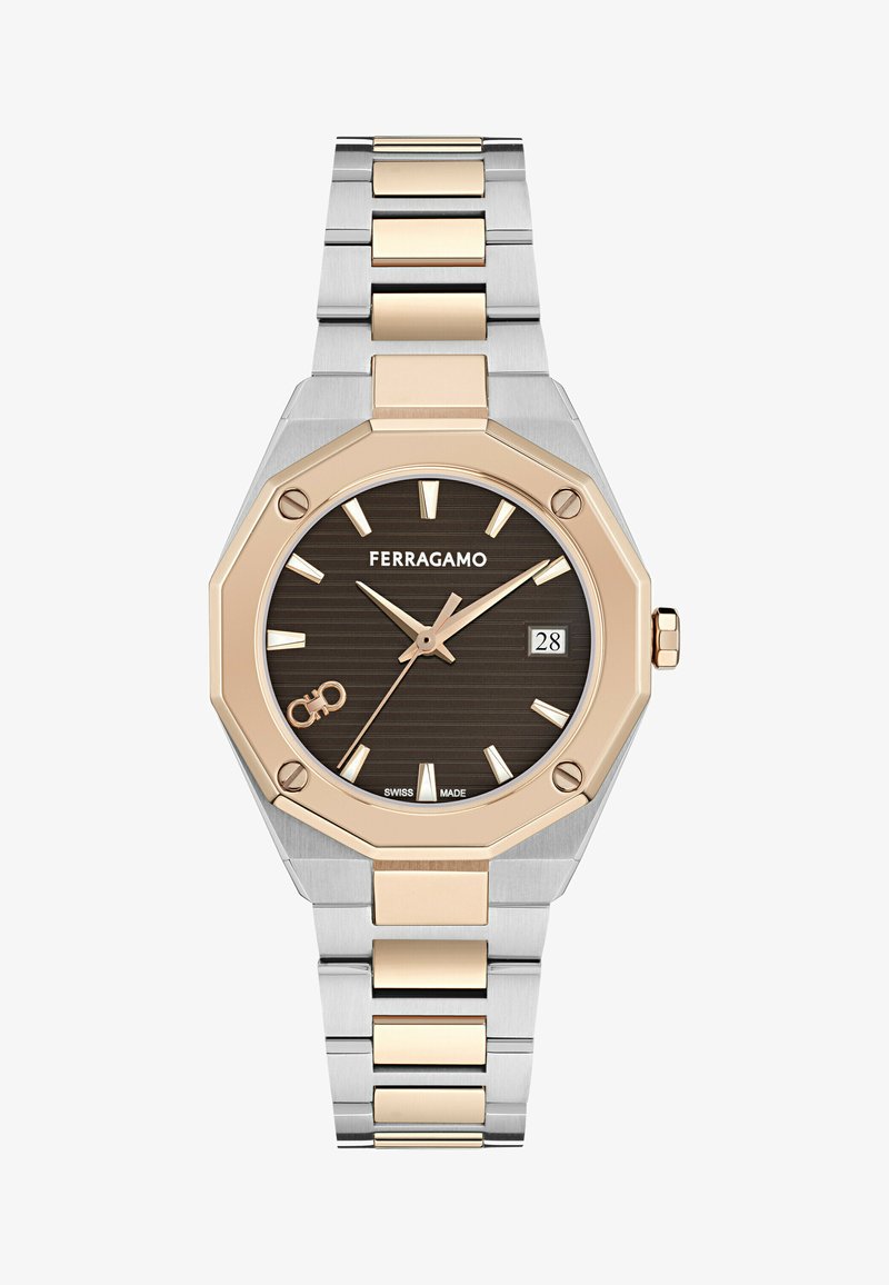 Ferragamo kell, millel on oktaatine roostevaba terasest korpus, pruun tekstuuriga kellapealne, kuldse tooni tunni markerid ja kahetooniline link-rakmed. Kuupäeva näidik 3. kohal.