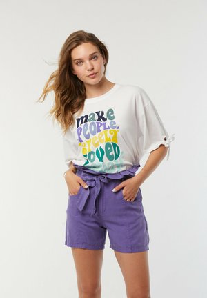 T-shirt blanc avec un texte multicolore, associé à un short violet avec une taille à nouer et des poches latérales. Casual, en mélange de coton léger.