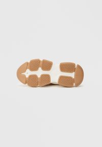 Suela de zapato con base de goma, presenta un patrón espina de pez en marrón claro, contrastado con segmentos acolchados blancos y una puntera redondeada.