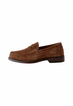 Mocassin en cuir suédé marron avec un talon bas empilé et des coutures de style mocassin sur fond blanc.