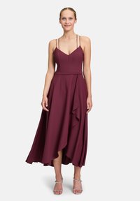 Burgunderfarbendes Midikleid mit tailliertem Oberteil, verstellbaren Spaghetti-Trägern und einem geschichteten asymmetrischen Rock. Hergestellt aus glattem Stoff mit fließender Textur.