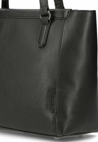 Schwarze Leder-Tragetasche aus strukturiertem Material, mit geformter Silhouette, silberfarbenen Beschlägen und einem geprägten Logo an der Seite.