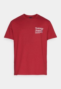 T-shirt en coton rouge avec col rond, manches courtes, et un logo blanc imprimé sur la poitrine gauche avec du texte. Texture lisse, coupe classique.