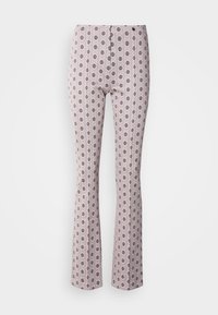 Pantalon rose clair avec des jambes évasées, décoré d'un motif floral circulaire noir répétitif.