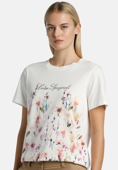 Camiseta blanca de manga corta con un colorido estampado floral en tonos rosa, púrpura y verde. "Luise Spagnol" está impreso en letras plateadas.
