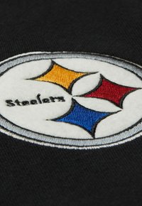 Schwarzer Stoff mit einem runden, bestickten Logo, das drei farbige Formen (gelb, rot, blau) zeigt, umrandet in Weiß, mit dem Text "Steelers" darunter.