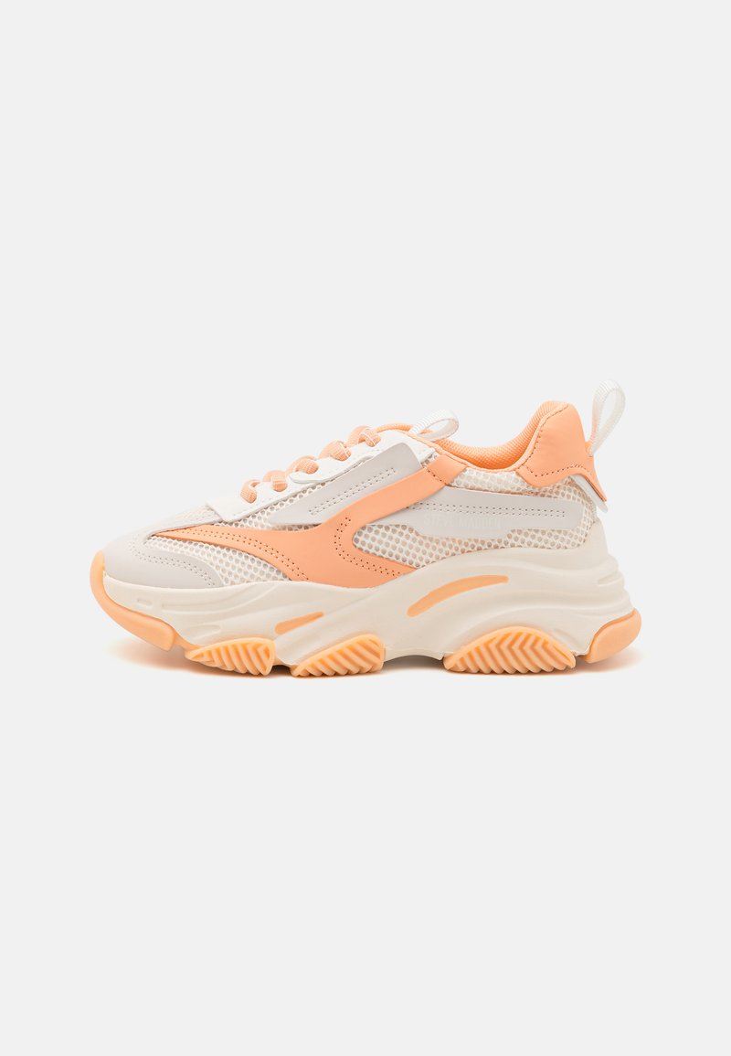 Zapatillas gruesas con parte superior de malla en tonos blanco y melocotón claro, suela de goma texturizada y detalles decorativos en el lateral.
