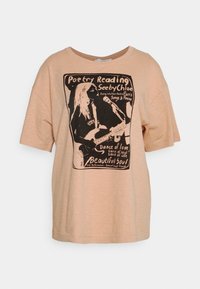Jasnoróżowa, luźna bawełniana koszulka z krótkim rękawem, z czarnym nadrukiem graficznym zawierającym tekst o wieczorze poezji i gitarzyście.
