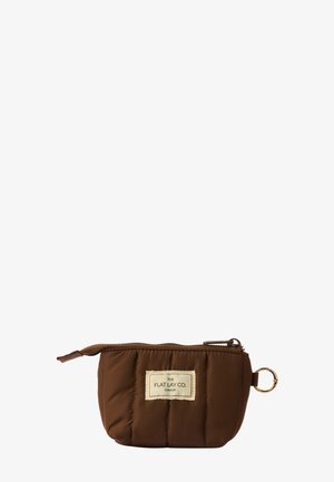 Brązowa pikowana saszetka z beżową etykietą z napisem "The Flat Lay Co. London" i złotym brelokiem przymocowanym do suwaka.
