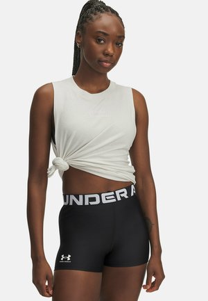 Lichtgrijs mouwloos topje met knoopdetail, gecombineerd met zwarte strakke shorts met een witte logoband en een klein logo op het been.