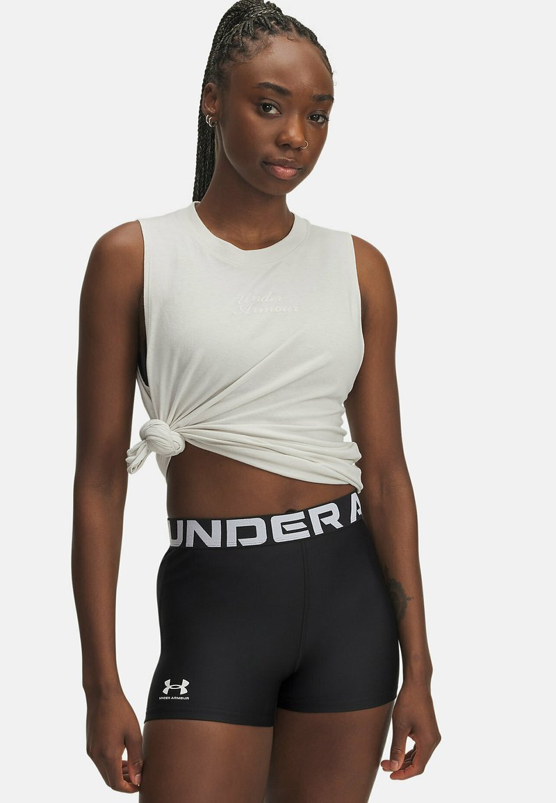 Lichtgrijs mouwloos topje met knoopdetail, gecombineerd met zwarte strakke shorts met een witte logoband en een klein logo op het been.