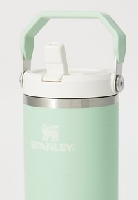 Lys grønn Stanley isolert vannflaske med hvit flip-top lokk og solid håndtak, designet for enkel bæring og drikking.