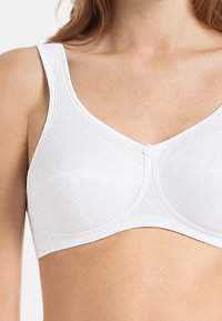 Reggiseno bianco con spalline larghe regolabili, tessuto testurizzato e design a V con stecche e coppe senza cuciture.